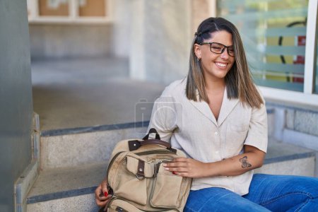 Téléchargez les photos : Jeune étudiante hispanique souriante confiante assise dans les escaliers de l'université - en image libre de droit