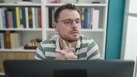 Téléchargez les photos : Jeune homme caucasien utilisant la pensée informatique à l'université de la bibliothèque - en image libre de droit