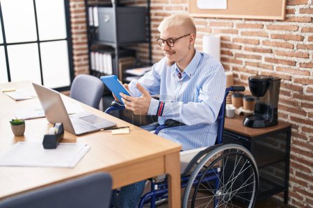 Foto de Young caucasian man business worker using touchpad sitting on wheelchair at office - Imagen libre de derechos