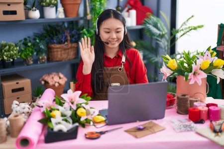 Photo for Young asian woman working at florist shop doing video call looking positive and happy standing and smiling with a confident smile showing teeth - Royalty Free Image