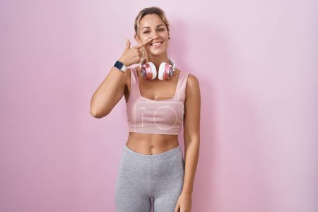 Photo for Young blonde woman wearing sportswear and headphones pointing with hand finger to face and nose, smiling cheerful. beauty concept - Royalty Free Image