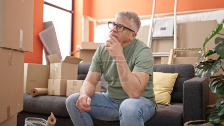 Photo for Middle age grey-haired man sitting on sofa with stressed expression at new home - Royalty Free Image