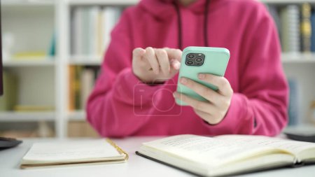 Foto de Joven estudiante rubia usando smartphone en la universidad de la biblioteca - Imagen libre de derechos