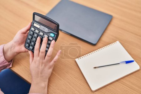 Photo for Young beautiful plus size woman using calculator at office - Royalty Free Image
