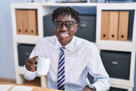 Téléchargez les photos : Africain Américain homme d'affaires travailleur souriant confiance boire du café au bureau - en image libre de droit