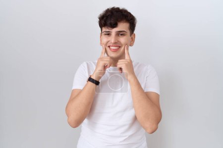 Foto de Joven hombre no binario vistiendo casual camiseta blanca sonriendo con la boca abierta, los dedos señalando y forzando sonrisa alegre - Imagen libre de derechos
