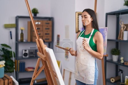 Photo for Young hispanic woman artist with doubt expression drawing at art studio - Royalty Free Image