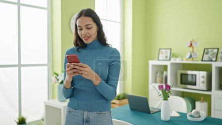 Photo for Young beautiful hispanic woman using smartphone standing at home - Royalty Free Image