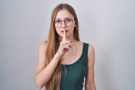 Photo for Young caucasian woman standing over white background asking to be quiet with finger on lips. silence and secret concept. - Royalty Free Image