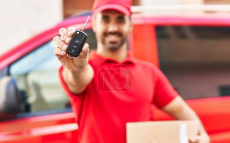 Photo for Young hispanic man courier holding package and car key at street - Royalty Free Image