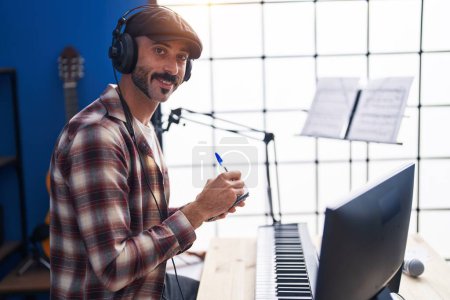 Photo for Young hispanic man musician listening to music composing song at music studio - Royalty Free Image
