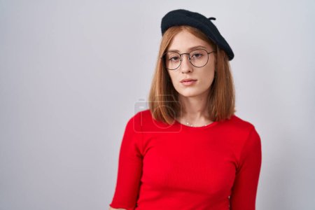 Photo for Young redhead woman standing wearing glasses and beret looking sleepy and tired, exhausted for fatigue and hangover, lazy eyes in the morning. - Royalty Free Image