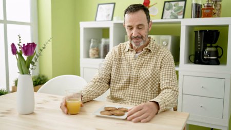 Foto de Hombre de mediana edad desayunando sentado en la mesa en casa - Imagen libre de derechos