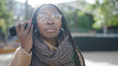 Téléchargez les photos : Femme africaine écoutant un message vocal au téléphone au parc - en image libre de droit