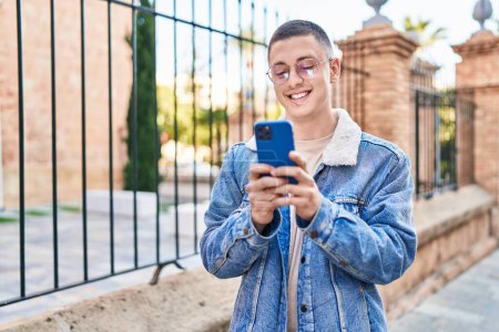 Foto de Joven hombre hispano sonriendo confiado usando smartphone en la calle - Imagen libre de derechos