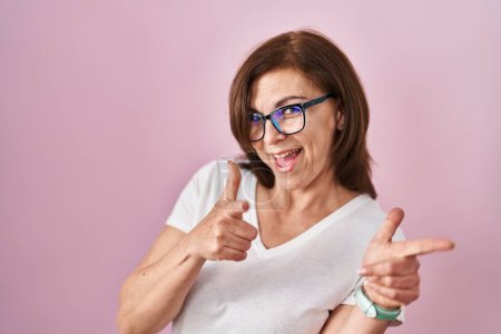 Photo for Middle age hispanic woman standing over pink background pointing fingers to camera with happy and funny face. good energy and vibes. - Royalty Free Image