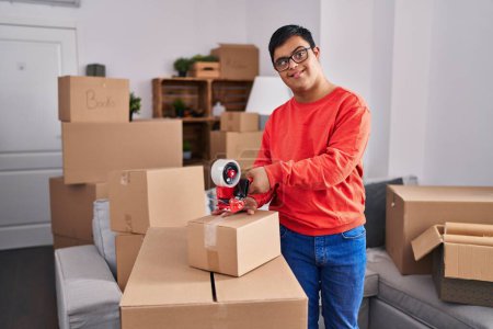 Foto de Síndrome de Down hombre sonriendo caja de cartón de embalaje seguro en un nuevo hogar - Imagen libre de derechos