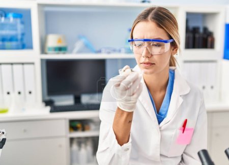 Photo for Young hispanic woman scientist looking sample at laboratory - Royalty Free Image