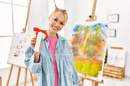 Photo for Young caucasian woman artist smiling confident holding diploma at art studio - Royalty Free Image