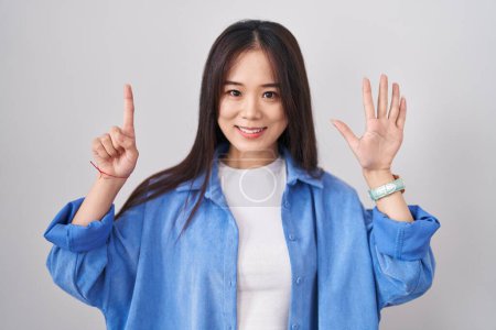 Téléchargez les photos : Jeune femme chinoise debout sur fond blanc montrant et pointant vers le haut avec les doigts numéro six tout en souriant confiant et heureux. - en image libre de droit