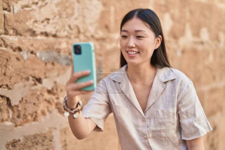 Photo for Chinese woman smiling confident making selfie by the smartphone at street - Royalty Free Image