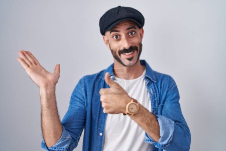 Téléchargez les photos : Homme hispanique avec barbe debout sur fond isolé montrant la main de la paume et faisant un geste correct avec les pouces levés, souriant heureux et joyeux - en image libre de droit
