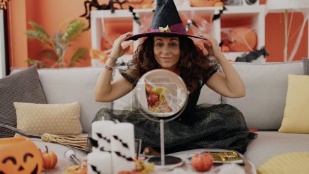 Téléchargez les photos : Femme hispanique du Moyen Âge portant un costume de sorcière pour la fête d'Halloween à la maison - en image libre de droit