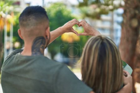 Foto de Hombre y mujer madre e hija haciendo gesto de corazón con las manos en el parque - Imagen libre de derechos