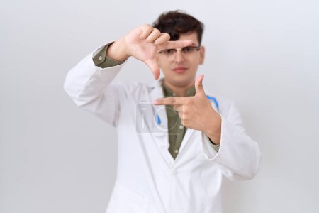 Photo for Young non binary man wearing doctor uniform and stethoscope smiling making frame with hands and fingers with happy face. creativity and photography concept. - Royalty Free Image