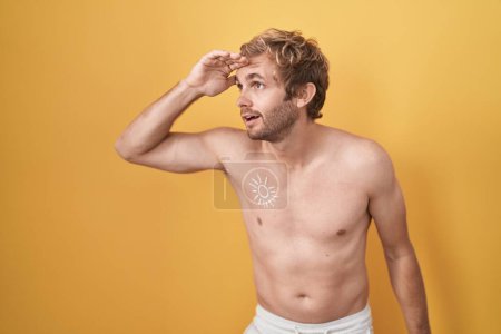 Photo for Caucasian man standing shirtless wearing sun screen very happy and smiling looking far away with hand over head. searching concept. - Royalty Free Image