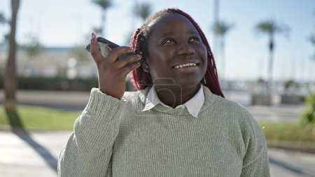 Photo for African woman with braided hair listening voice message with smartphone at street - Royalty Free Image