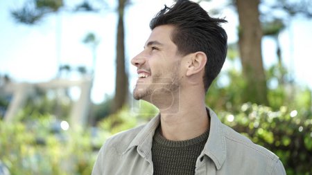 Téléchargez les photos : Jeune homme hispanique souriant confiant regardant vers le côté au parc - en image libre de droit