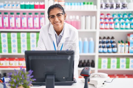 Photo for Young beautiful hispanic woman pharmacist smiling confident using computer at pharmacy - Royalty Free Image