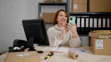 Téléchargez les photos : Jeune rousse femme commerce électronique travailleur d'entreprise en utilisant un smartphone au bureau - en image libre de droit