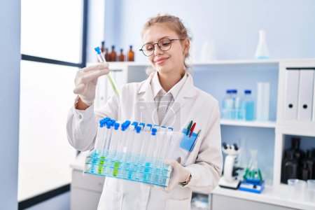 Foto de Joven mujer rubia científica sosteniendo tubos de ensayo en laboratorio - Imagen libre de derechos