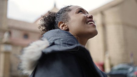 Foto de Mujer afroamericana sonriendo confiada mirando al cielo en la calle - Imagen libre de derechos