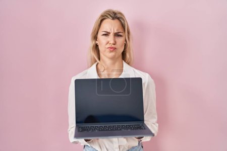 Photo for Young caucasian woman holding laptop showing screen skeptic and nervous, frowning upset because of problem. negative person. - Royalty Free Image