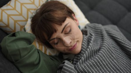 Téléchargez les photos : Young caucasian woman sleeping on the sofa covered with blanket at home - en image libre de droit