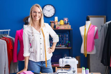Photo for Young blonde woman tailor smiling confident standing at sewing studio - Royalty Free Image