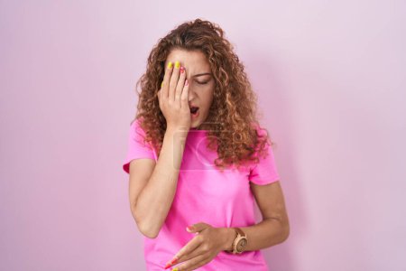 Photo for Young caucasian woman standing over pink background yawning tired covering half face, eye and mouth with hand. face hurts in pain. - Royalty Free Image