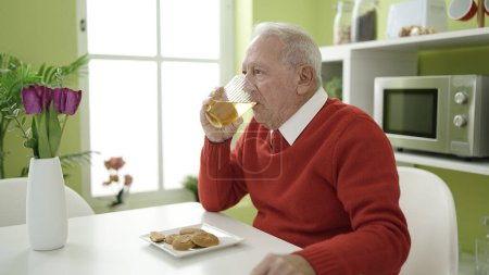 Photo for Senior eating cookies and drinking juice at home - Royalty Free Image