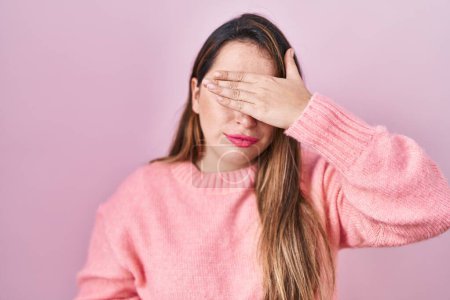 Photo for Young hispanic woman standing over pink background covering eyes with hand, looking serious and sad. sightless, hiding and rejection concept - Royalty Free Image