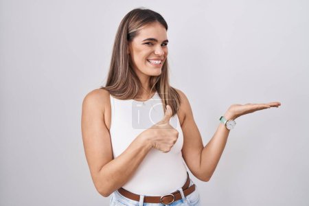 Téléchargez les photos : Jeune femme hispanique debout sur fond blanc montrant la main de la paume et faisant un geste correct avec les pouces levés, souriant heureux et joyeux - en image libre de droit