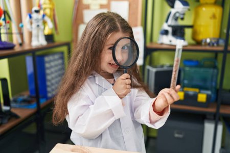 Téléchargez les photos : Adorable élève hispanique fille à la recherche d'échantillon avec loupe à la salle de classe de laboratoire - en image libre de droit