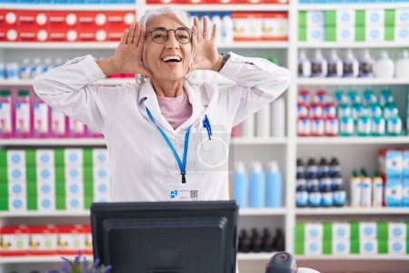 Photo for Middle age woman with tattoos working at pharmacy drugstore smiling cheerful playing peek a boo with hands showing face. surprised and exited - Royalty Free Image