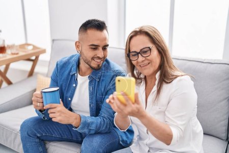 Photo for Man and woman mother and son using smartphone drinking coffee at home - Royalty Free Image