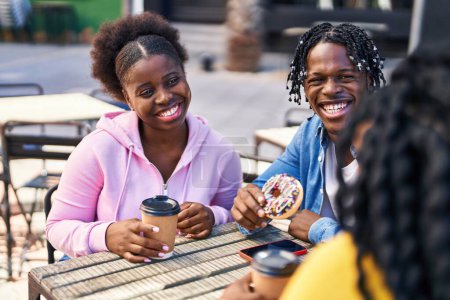 Foto de Amigos afroamericanos desayunando sentados en la mesa en la terraza de la cafetería - Imagen libre de derechos