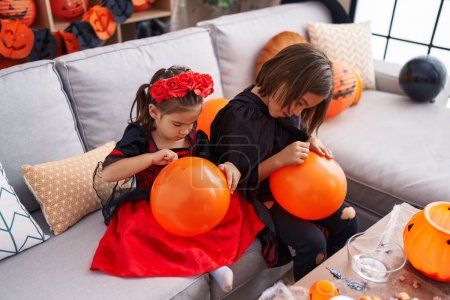 Foto de Adorable chico y chica teniendo halloween fiesta dibujo en globo en casa - Imagen libre de derechos