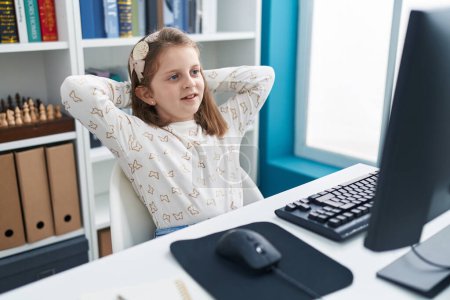 Photo for Adorable blonde girl student using computer resting with hands on head at classroom - Royalty Free Image