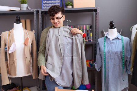 Téléchargez les photos : Non binary man tailor smiling confident holding jacket at atelier - en image libre de droit